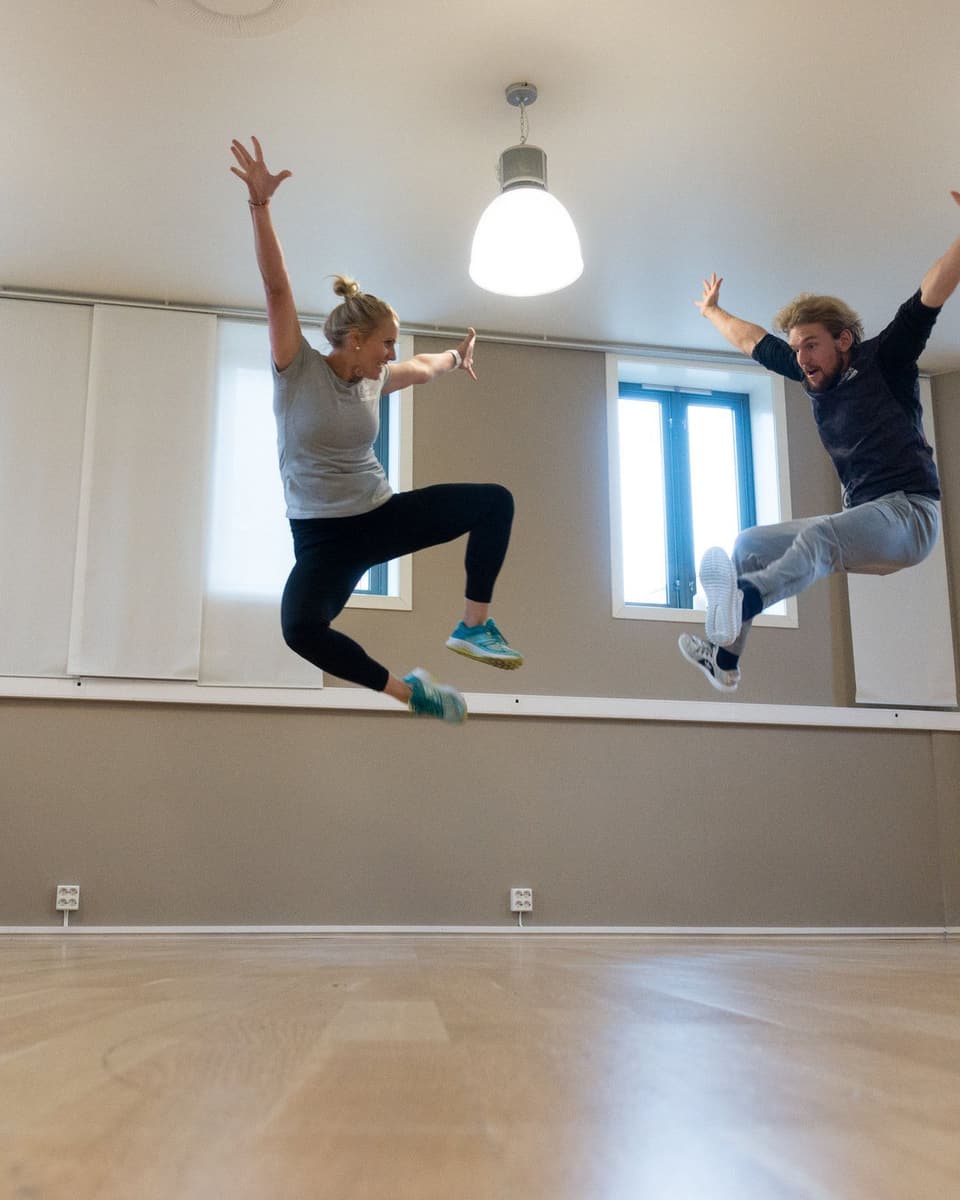 To blide mennesker hopper høyt i den lyse treningssalen hos Olympus Trening